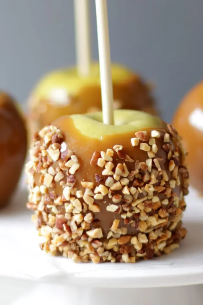 Homemade caramel apples with nuts on them.